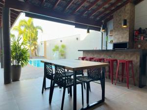 a table and chairs in a restaurant with a pool at Refúgio com Fogueira, Piscina, Bilhar e Ar condicionado in Nova Odessa