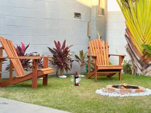 two chairs and a bottle of wine sitting on the grass at Refúgio com Fogueira, Piscina, Bilhar e Ar condicionado in Nova Odessa