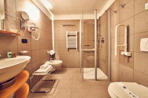 a bathroom with a shower and a toilet and a sink at iH Hotels Courmayeur Mont Blanc in Courmayeur
