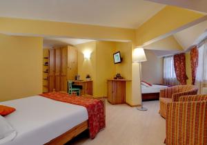 a hotel room with a bed and two chairs at iH Hotels Courmayeur Mont Blanc in Courmayeur