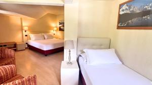 a hotel room with two beds and a chair at iH Hotels Courmayeur Mont Blanc in Courmayeur