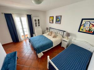 a bedroom with a bed and two chairs in it at Milfontes Villa in Vila Nova de Milfontes