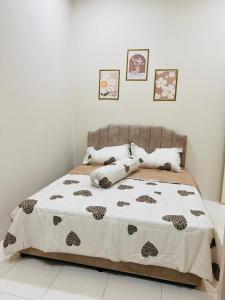 a bed with a brown and white comforter and pillows at Elora Homestay in Tampin