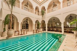 an indoor pool in a building with tables and chairs at Maison Zamane in Marrakesh