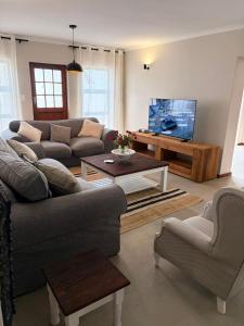a living room with a couch and a tv at River & Salt at Stilbaai in Stilbaai-Oos