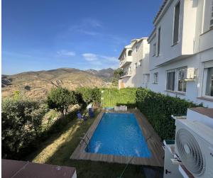 a swimming pool in a yard next to a building at Alojamiento Colinas in Monachil