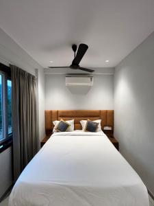 a bedroom with a white bed with a ceiling fan at Hotel SERENE PRAIA in Visakhapatnam