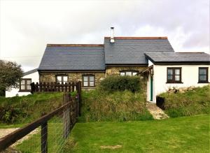 a house on a hill with a fence at Ysgol Hill Cottage in Rosebush