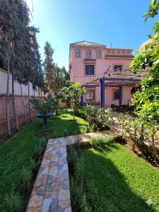 a garden in front of a pink house at Villa RAHA villa entière in El Aggada