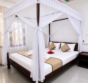 a bedroom with a canopy bed with flowers on it at Friendly Waves Resort Arugambay in Pottuvil