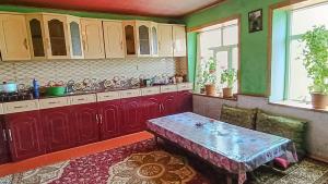 a kitchen with red cabinets and a table in it at Sarvan's Khinalig Riverside Montain House in Xınalıq