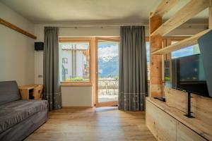 a living room with a couch and a television at Hotel Vallechiara in Bormio