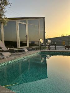 a swimming pool with two chairs and a house at EmberHaus Retreat with Private Pool in Kafr ‘Ubaydā