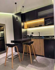 a kitchen with a counter and two stools and a sink at EmberHaus Retreat with Private Pool in Kafr ‘Ubaydā