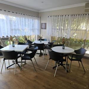 a dining room with tables and chairs and windows at Rest-a-While Guest House - Pretoria in Pretoria