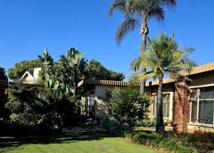 a house with palm trees in front of it at Rest-a-While Guest House - Pretoria in Pretoria
