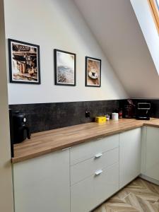 a kitchen with white cabinets and pictures on the wall at Na Fali Marszałka in Mielenko