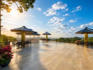 a large patio with tables and umbrellas on top at Eva & Era Paradise in Solan