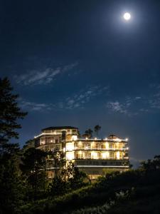 a large building on a hill at night with the moon at Eva & Era Paradise in Solan