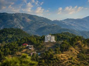 a building on a hill with mountains in the background at Eva & Era Paradise in Solan +9 photos
