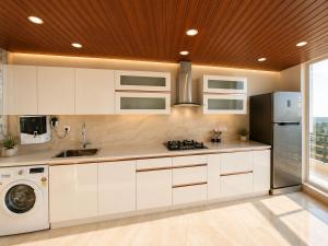 a kitchen with white cabinets and a washer and dryer at Eva & Era Paradise in Solan