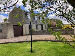 a house with a garage and a pole in the grass at Ardmuir in Turriff