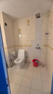 a bathroom with a toilet and a red bucket at Secret kitchen rooms in Candolim