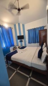 a bedroom with a large bed with blue curtains at Secret kitchen rooms in Candolim