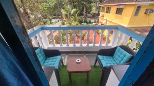 a balcony with two chairs and a table and a white railing at Secret kitchen rooms in Candolim
