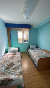 two beds in a room with blue walls at Nestorovski House in Bitola