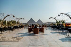 a patio with tables and chairs with pyramids in the background at Hotel Comfort Giza in Cairo