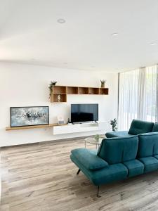 a living room with a blue couch and a tv at Sea't La Vie Villas in Hamallë