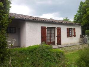 a small white house with brown wooden doors at Gite du Fourbas in Belmont-Sainte-Foi