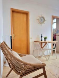 a rattan chair in a room with a table and a clock at Casa da Anunciada | Old Town in Setúbal