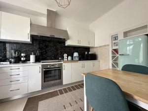 a kitchen with white cabinets and a wooden table at Villa Populo in Ponta Delgada