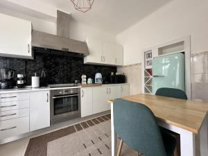 a kitchen with white cabinets and a wooden table at Villa Populo in Ponta Delgada +37 photos