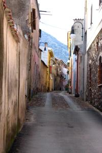 an empty alley with buildings and a mountain in the background at B&B CasaCorì in Orosei
