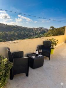 two chairs and a table with two glasses of wine at Gmiel in-Natura B&B in Għajn il-Kbira