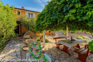 a patio with a table and chairs under a tree at Milena Sea & Mountain View in Zubovići