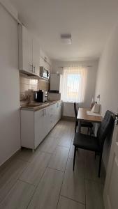 a kitchen with white cabinets and a table with a chair at Apartament MARIO in Târgu Ocna