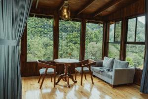 a living room with a table and a couch and windows at Lauraceas Lodge in San Gerardo de Dota