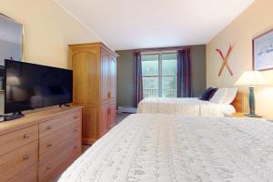 a bedroom with two beds and a flat screen tv at Long Trail House - 230 in Stratton