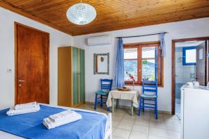 a bedroom with a bed and two blue chairs and a table at Stamatis Rooms in Skopelos Town