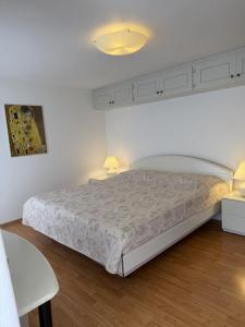 a white bedroom with a bed and two lamps at Casa Chatelain in Ronco sopra Ascona