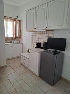 a kitchen with white cabinets and a television on a refrigerator at AVRA Apartments & Studios in Frý