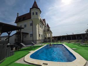 a person swimming in a pool in front of a building at Castle Csányi in Livezeni
