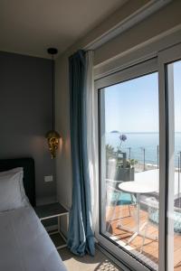 a bedroom with a bed and a view of the ocean at Acciuga Hotel in Laigueglia