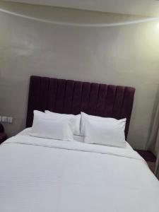 a large bed with white sheets and pillows at Atlantis De Maria Hotels in Akure