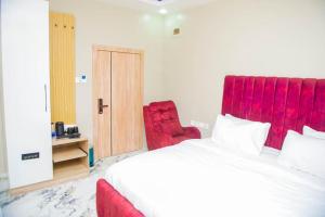 a bedroom with a large bed and a red chair at Atlantis De Maria Hotels in Akure