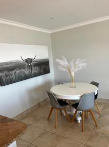 a dining room with a table and a picture of a bull at 3 Bedroom - Salt Rock Beach Pad in Ballito